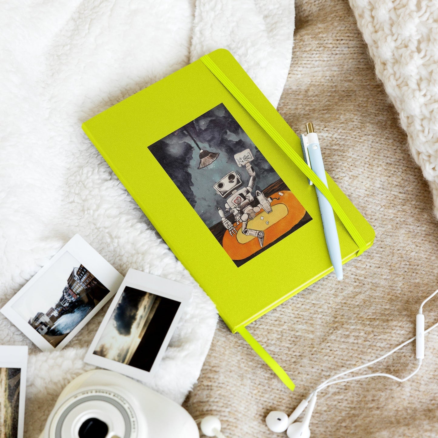 Lime green hardcover notebook with a playful robot illustration, featuring an elastic closure, ribbon marker, and expandable inner pocket, on a cozy surface.
