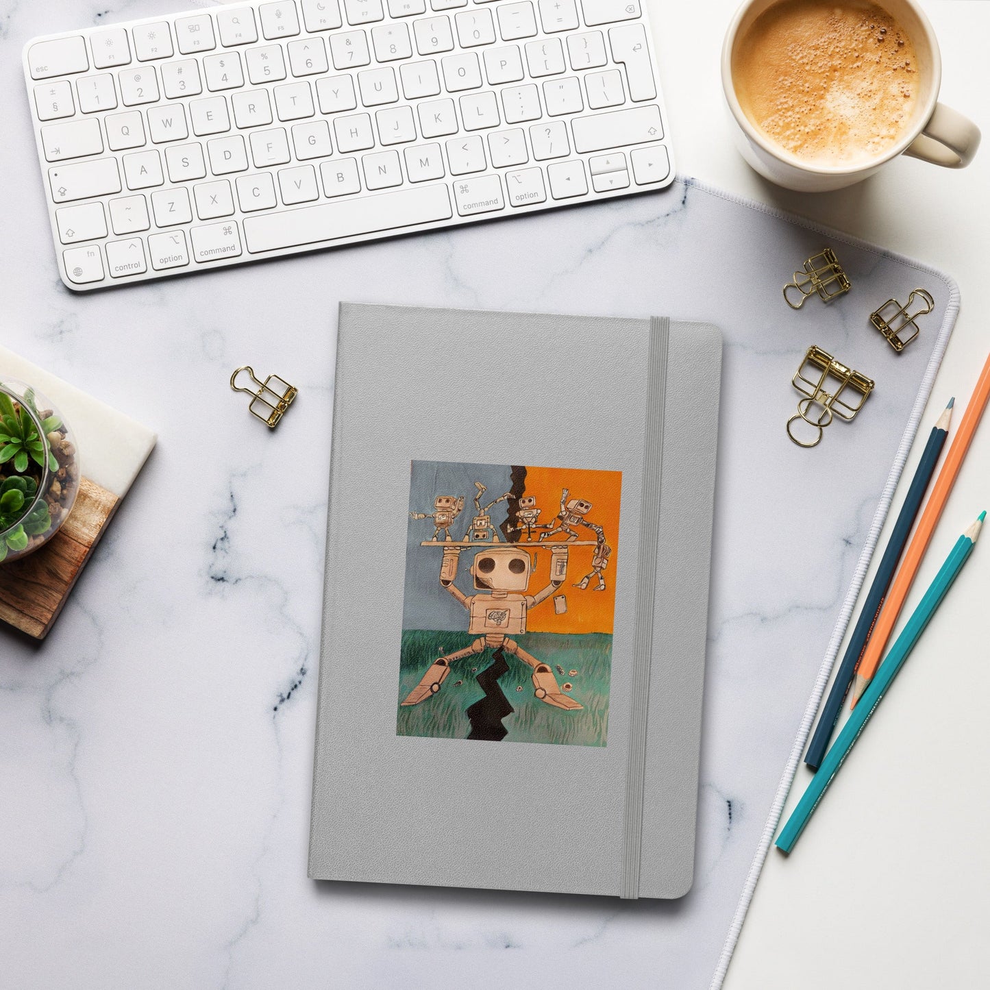 Hardcover bound journal with elastic closure and ribbon marker on marble desk with coffee and keyboard.